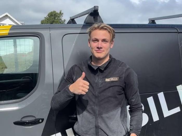 Fredrik Tuen i arbeidsklær gir tommel opp foran ET Byggs firmabil.